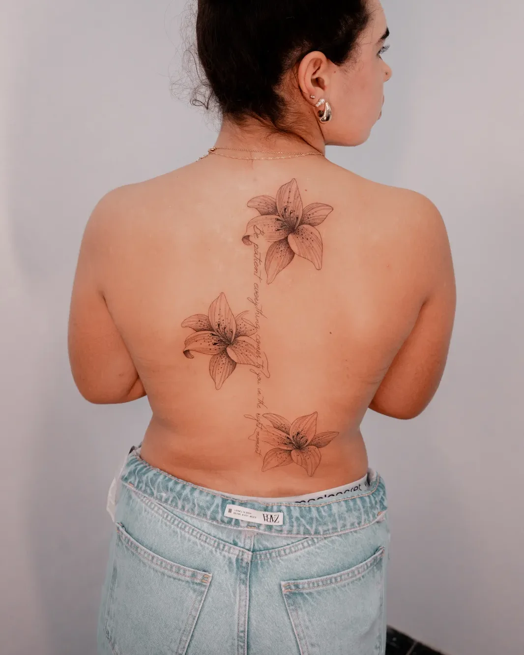 Botânico lilies tattoo along the spine