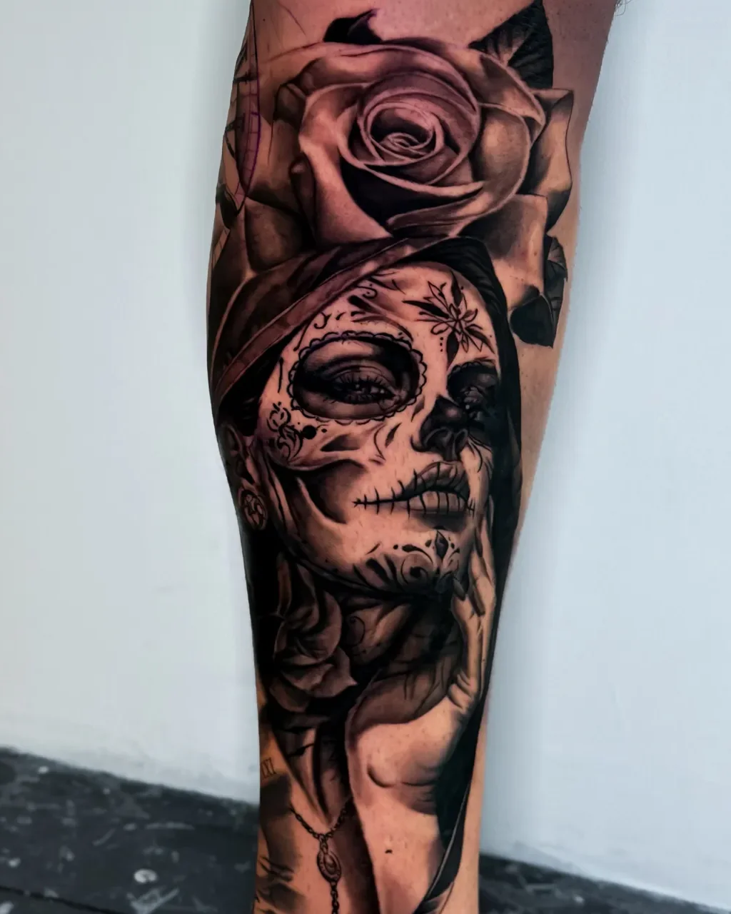 Tatuagem de realismo de catrina com rosa na perna