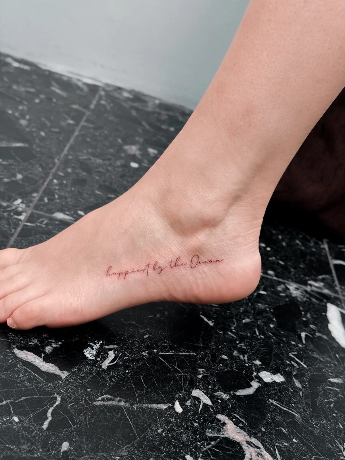 Fine line handwritten ocean quote foot tattoo by Hugo Gonzalez