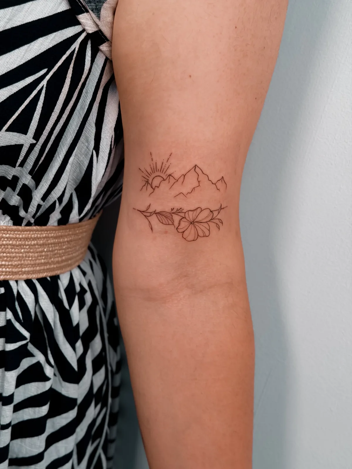 Fine line sunrise, mountains and flowers tattoo by Hugo Gonzalez